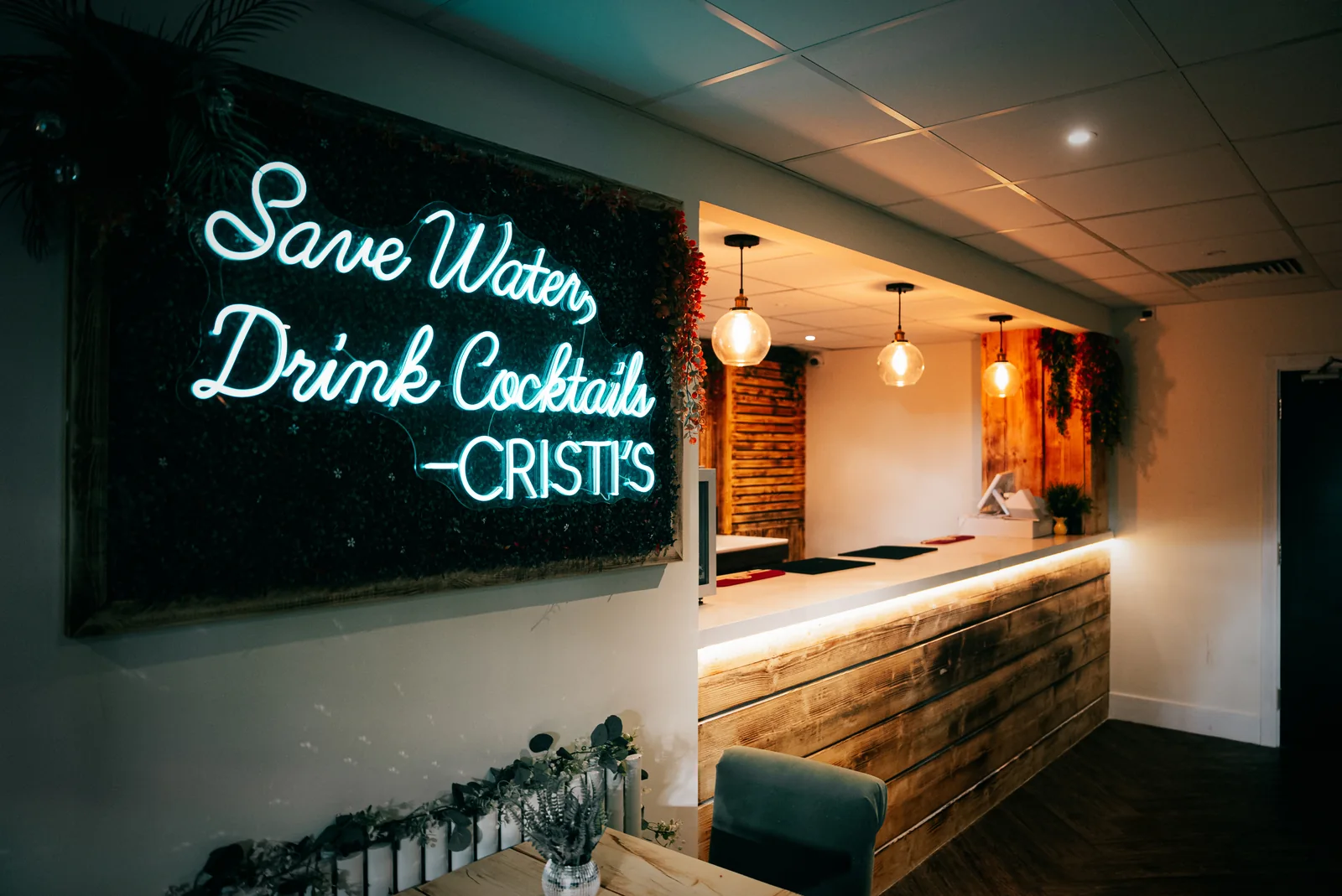 Cocktail neon sign and warm pendant lighting beside the private bar at Cristi’s